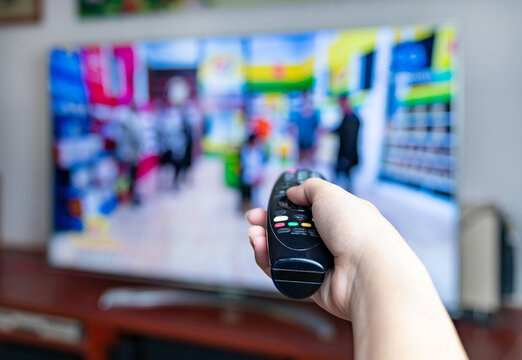 Male hand holding TV remote control for change program.