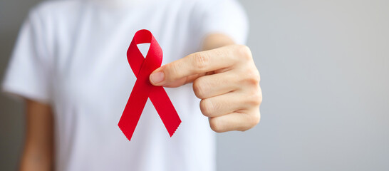 Hand holding Red Ribbon for December World Aids Day (acquired immune deficiency syndrome), multiple myeloma Cancer Awareness month and National Red ribbon week. Healthcare and world cancer day concept - obrazy, fototapety, plakaty