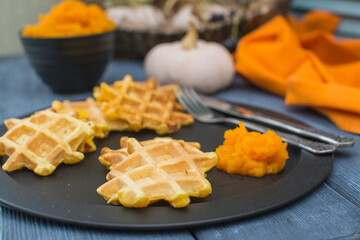 Viennese pumpkin waffles with pumpkin puree on a black metal plate.