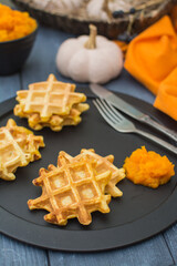 Viennese pumpkin waffles with pumpkin puree on a black metal plate.