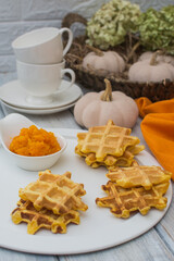 Viennese pumpkin waffles with pumpkin puree on a white metal plate.
