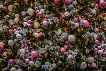 Lots of white and pink ornaments on a flocked Christmas tree
