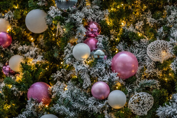 Obraz na płótnie Canvas Lots of white and pink ornaments on a flocked Christmas tree