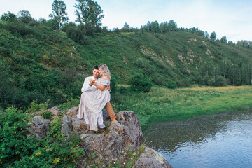 Romantic inloved couple sitting on rocks by the river.
