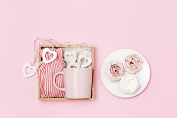 Gift box with pink mug, marshmallow and surprise in textile bag, sweet care package decorated with garland of hearts