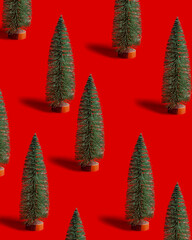 Pattern with green shining Christmas tree on red background. Bright minimal New Year layout with mini festive fir, xmas decor ornament, winter holiday