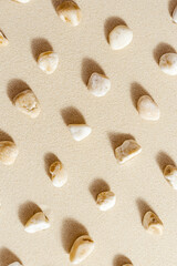 Sea stones neutral beige color on natural fine sand background. Styled pattern from natural white yellow pebbles, monochrome tones. Spa minimal background