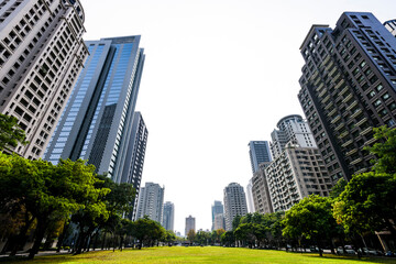 Low-angle view of green park space and modern buildings on both sides in downtown Taichung, Taiwan. here is near the National Taichung Theater.
