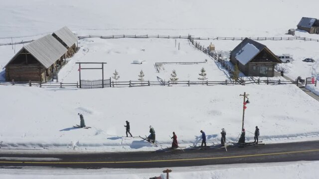 Tuva men dressed in traditional clothing walking in fur ski in snow, Hemu Village, Xinjiang, China. Epic aerial view