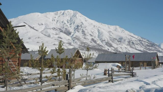 Cute log cabin village sitting at the bottom of snow mountain, winter day