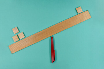 Wooden cubes on the scale from the ruler, that are not balanced, on blue paper background