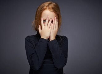 red-haired girl with freckles on her face in a black sweater posing