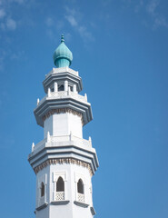 Fototapeta na wymiar Mosque minaret against blue sky. Copy space.
