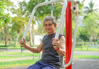 an old man doing exercise at outdoor fitness equipment in the park, concept health care in elderly people, lifestyle