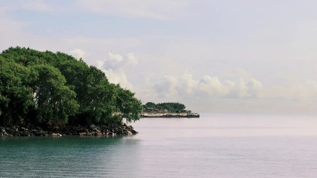 A shot of a beautiful coastal island along the Panama Canal, a gentle breeze causing ripples on the surface of the calm ocean waters, Panama City