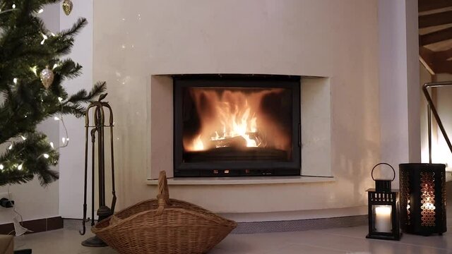 Still shot of a Cozy modern fireplace during the christmas eve celebration with a pine tree and a wicker empty basket