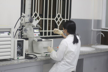 Asian woman scientist operating a rotary evaporator to make an experiment in the laboratory