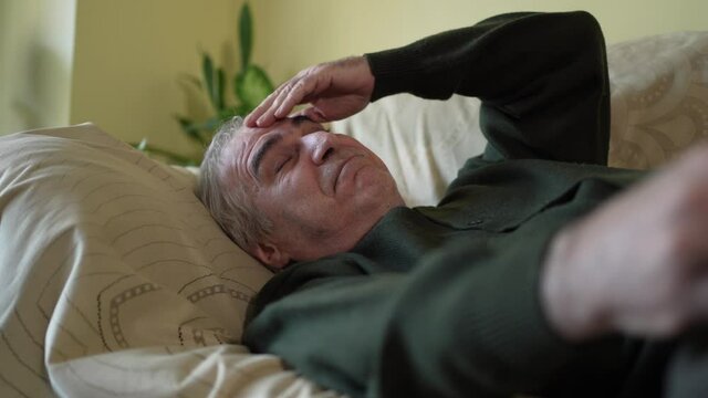Elderly Senior Men Having a Headache Feling Pain Laying Down