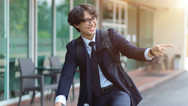 Happy businessman riding bicycle to work in the morning.