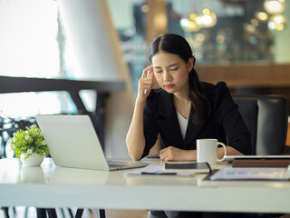 Fototapeta premium A businesswoman gets a headache while trying to solve problems at work