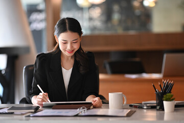 Fototapeta na wymiar Charming businesswoman using digital tablet in modern office.