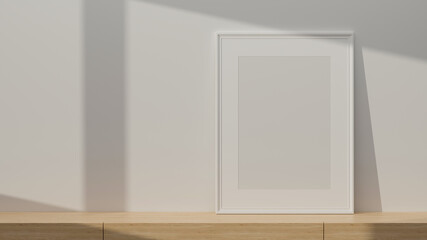 White portrait poster frame mockup standing on wooden table with copy space
