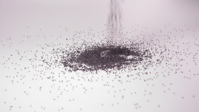 Dry Organic Poppy Seeds Fall In Heap Against White Background In Studio. close up