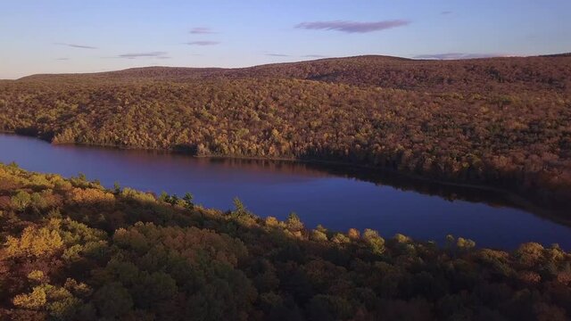 Aerial pan of autumn forest and still Lake of the clouds in Michigan