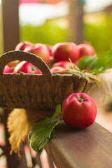Ripe red apples in a wicker basket on a wooden table.
