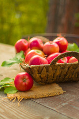 Ripe red apples in a wicker basket on a wooden table.