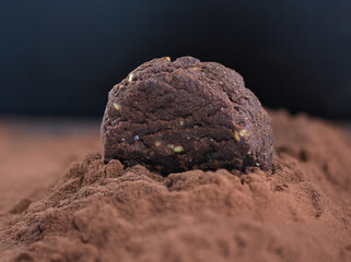Chocolate craft cookie with nuts on top of the cocoa powder pile
