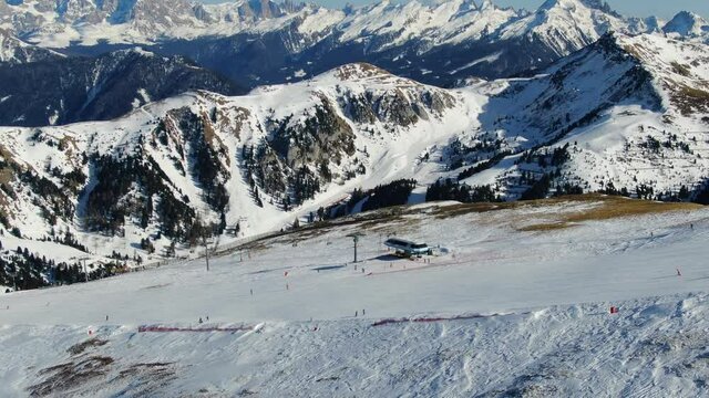 Aerial drone shot circle around of ski riders going down the hill with a nice parallax effect and some beautiful peaks of the tyrol mountains in the background