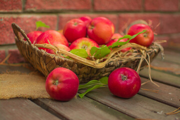 Ripe red apples in a wicker basket on a wooden table.