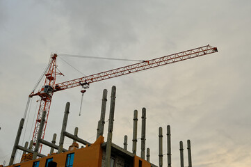 High rise construction crane on background of an unfinished multi storey and multi apartment residential building.