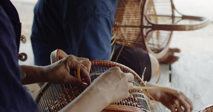  2 Thai female farmers weave basket in traditional Thai art patterns to sell as extra income in countryside of Thailand.	