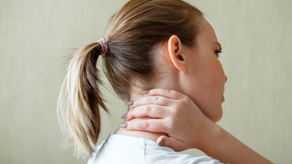 Naklejka premium Neck shoulder pain, cervical vertebrae. Woman holds neck with pain cervical muscle spasm by hand at home. Healthcare medical concept. Long web banner