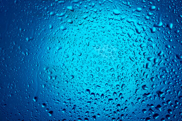Water drops on glass on a blue background.