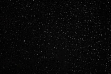 Water drops on glass on a black background.