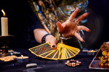 The fortune teller holds a fan of cards in her hands and casts a spell with her hand. Close-up. The concept of divination, magic and esotericism - obrazy, fototapety, plakaty