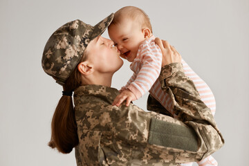 Indoor shot of happy emotional soldier woman returning home from army, lifting infant daughter and...