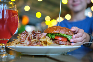 Closeup of tasty burger and french fries with meat on plate in restaurant