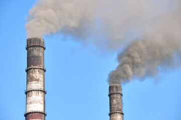 Closeup of thermal power plant high pipes with black smoke moving upwards polluting atmosphere....