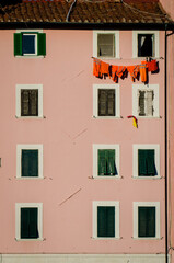 Fototapeta premium Vestiti da lavoro arancioni stesi ad asciugare fra le finestre di un palazzo di Livorno