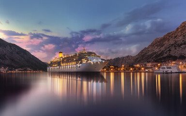 Mesmerizing view of a huge ship on the water under high mountains at night Kotor Bay, Montenegro