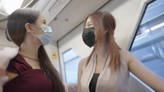 Two female employee enjoy relax talking while using a public transportation during a day, woman on beauty talking and body care, fashionable female employee, femininity society, friendship having fun