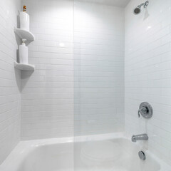 Square frame Alcove bathtub with glass wall divider and a wall with white tiles