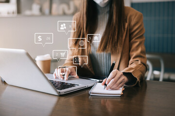 Business woman use a laptop computer and take notes in the notebook at the office desk.