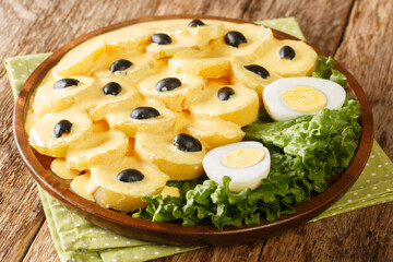Tasty Papa a la Huancaina Potatoes in Spicy Cheese Sauce and boiled eggs close up in the plate on the table. Horizontal