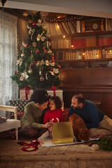 Family in Christmas morning opening present together