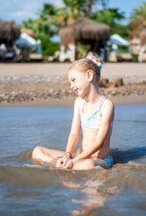 Little girl playing on the beach by the sea